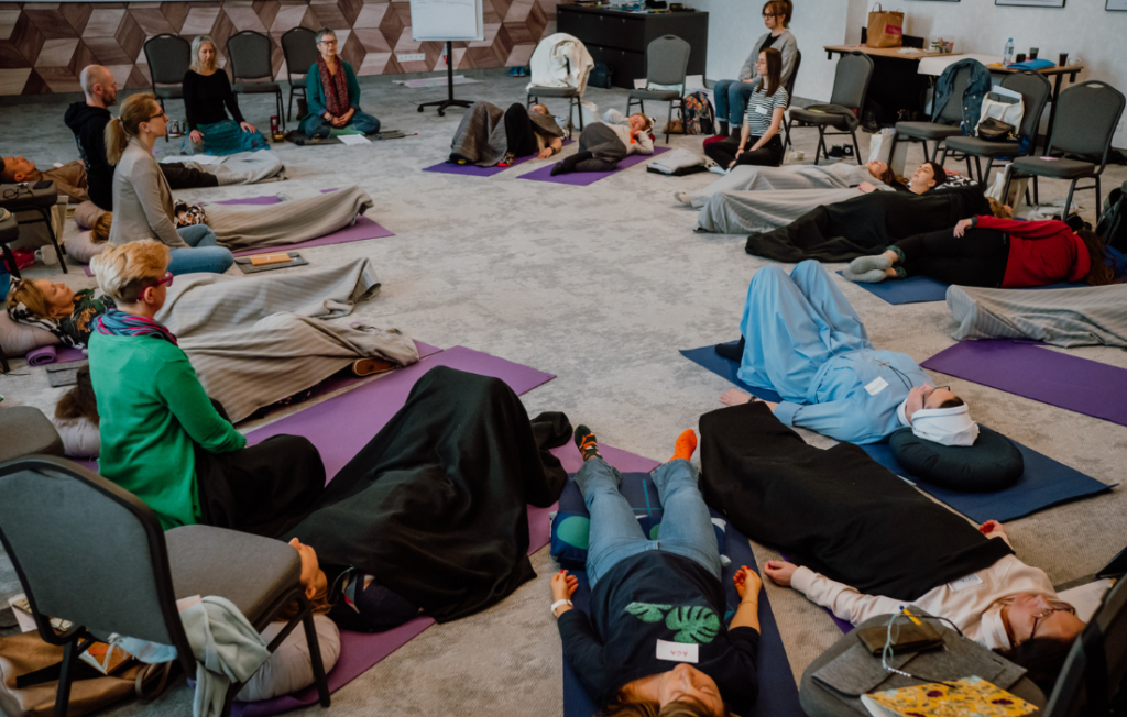 Grupa osób praktykująca Mindfulness podczas warsztatów